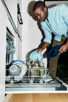 Man Putting Dishes in a Dishwasher 