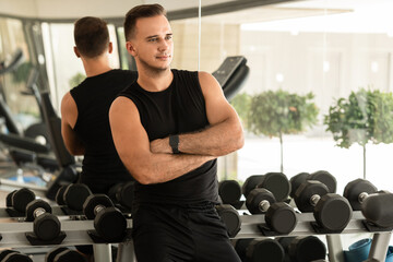 Young athletic man in a free weight zone of the modern gym