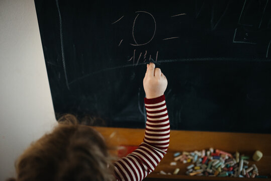 close up of toddler writing on chalkboard