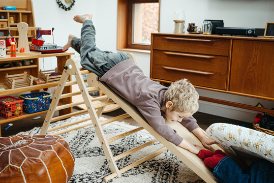 siblings enjoying climbing and sliding on a pikler triangle