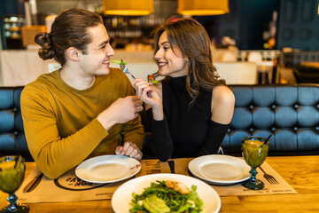 Happy couple eating salad for dinner at cafe or restaurant terrace