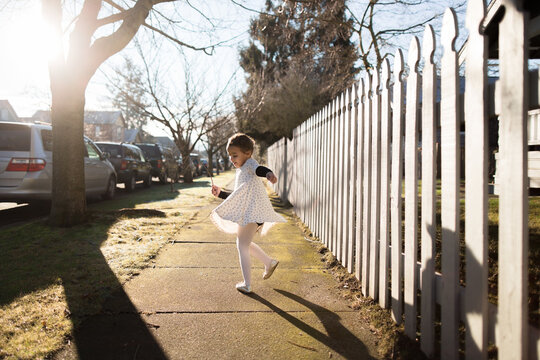 Girl dances on sunny sidewalk