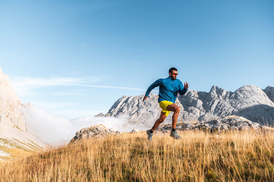 Athletic man running on hill in mountains 