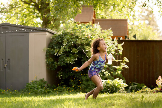  Laughing girl runs while sprayed with water