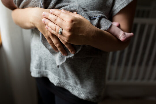 Hands of mother with wedding ring holding baby