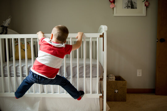 Energetic boy climbs on crib