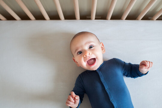 Funny Baby with Big Smile in Crib