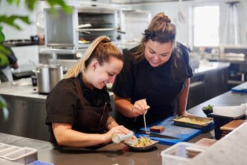 Chefs plating food in a fine dining restaurant kitchen