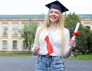 Happy female student graduate with Poland flag and diploma. Graduation day at the university.