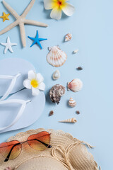 Summer beach background design concept with shells, hat, slipper on blue background.