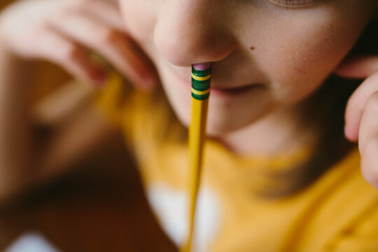 A child sticks a pencil up their nose
