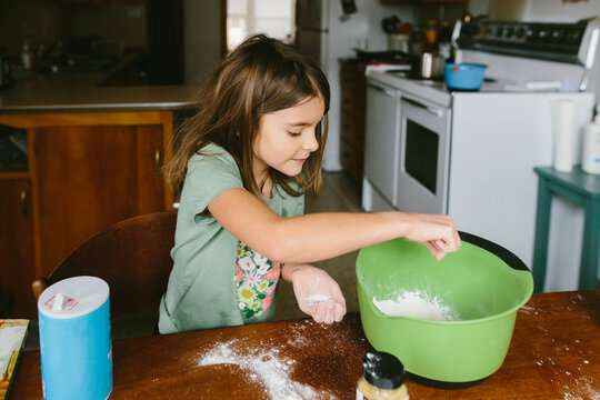 A young girl mixes ingredients to bake muffins at home