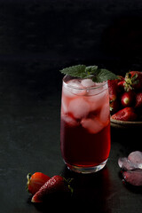 Red drink, cocktail with strawberries in a glass on a black background. Summer frozen drinks in a dark way