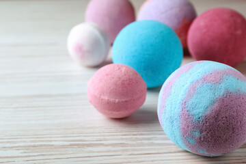 Colorful bath bombs on white wooden table, space for text