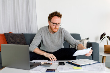 Man Reviews Statement While Calculating Annual Expenses For His Startup