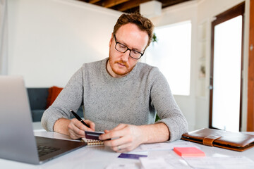 Man With Glasses Calculates Annual Expenses For His Work From Home Startup