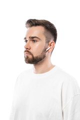 Handsome bearded man in white clothes  using wireless earbuds on white background