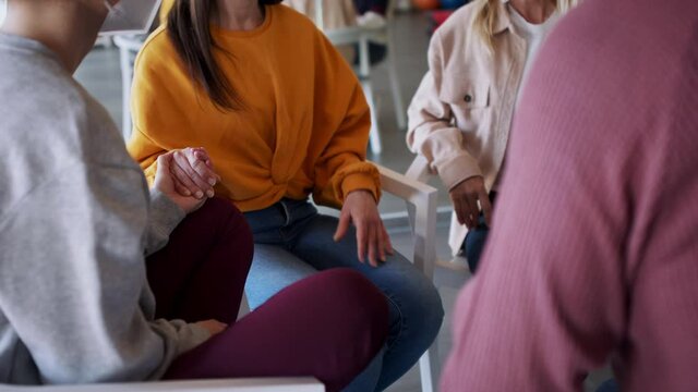 Group of people on therapy session, members holding each other by hand.