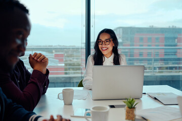 Successful smiling young woman sitting with his multiethnic colleagues at a corporate business...