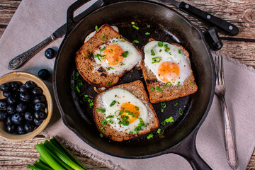 Fried eggs in a whole made with rye bread in a cast iron pan