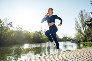Fototapeta na wymiar Athletic fit young woman jogging early in the morning in park