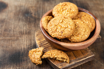 Healthy homemade oatmeal cookies with peanuts in a wooden bowl on a brown kitchen table closeup