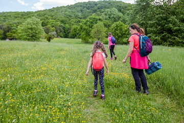 Fototapeta premium Family hiking , spring day, green fields, nature landscape, mother with daughters