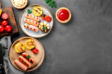  Grilled sausages with vegetables and sauces. Summer BBQ with sausages, corn and tomatoes. Top view, copy space for text