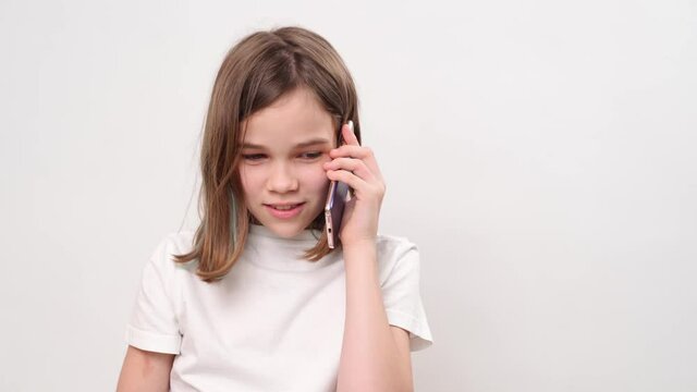 The teenage girl talking on smartphone and laughs on a white background. children's dependence on gadgets and social networks.