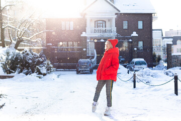 Young stylish blonde woman on the street has fun, posing in snowy, frosty