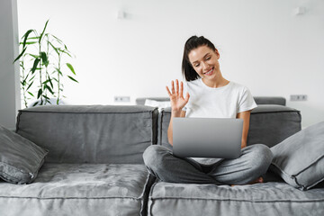Smiling young woman in casual wear using laptop