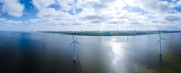 offshore windmill park with clouds and a blue sky, windmill park in the ocean aerial view with wind turbine Flevoland Netherlands Ijsselmeer. Green energy 
