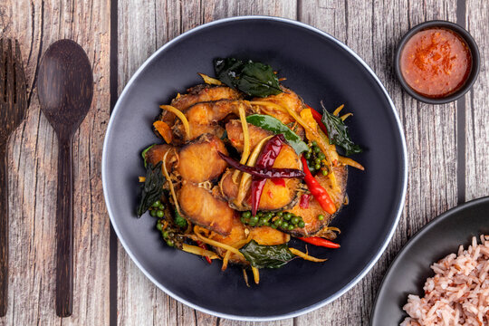 Flat lay spice stir-fried snakehead fish with herbs and vegetables like fingerroot, green peppercorns, kaffir lime leaves and holy basil leaves, a healthy Thai food dish called pad cha pla chon.