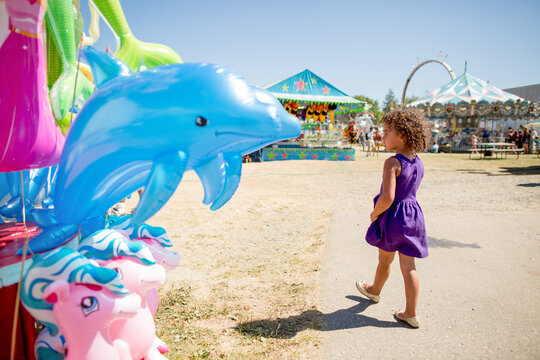 Girl walks past inflatable dolfin at county fair