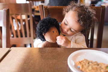 Toddler shares cookie with doll