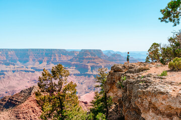 A young man on the edge of a cliff looks at a beautiful panoramic  landscape in the Grand Canyon....