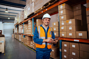 Smiling portrait of a male warehouse worker holding digital tablet in hand looking at camera
