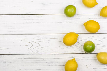 Ripe limes and lemons on white wooden boards, top view, copy space. food background. Summer concept