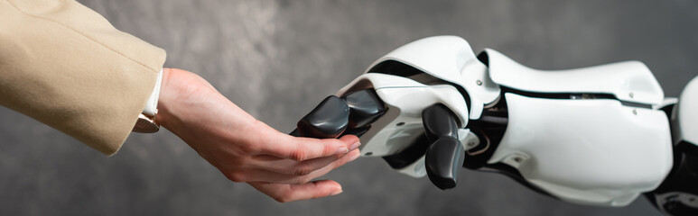 cropped view of businesswoman touching hand of robot, banner