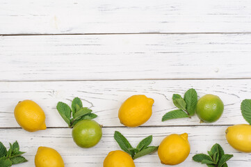 Ripe limes, lemons, mint on white wooden boards, top view, copy space. summer background;