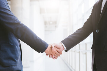 Two confident business man shaking hands during a meeting in the office, success, dealing and background is tower.