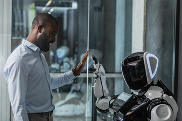 happy african american businessman giving high five to robot in office
