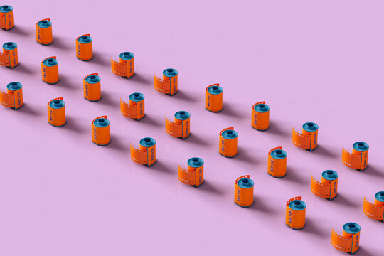 Orange film rolls on pink background neatly arranged