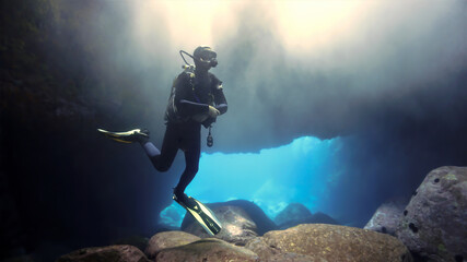 Obraz na płótnie Canvas Scuba diver inside a cave with magic light
