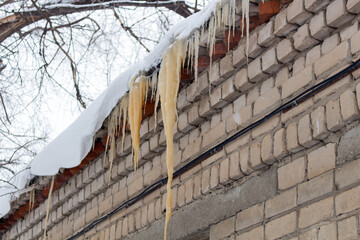 Dirty icicles hang on the roof of the building.