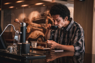 Hipster style customer drinking hot drip coffee at cafe,he tasted the flavor together and looking smart phone at the cafe counter.