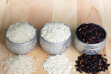 Three types of Thai rice in a silver container. On wood background and copy-space.
