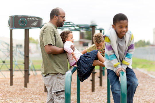 Father lifts girl onto parallel bars