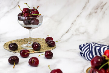 bowl of cherries on marble background and wicker tablecloth