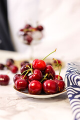 Fototapeta na wymiar bowl of cherries on marble background and wicker tablecloth
